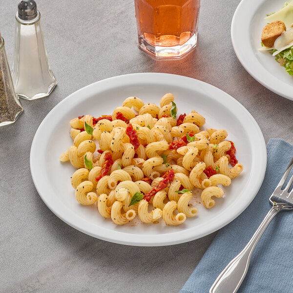 A plate of pasta with a fork on an Acopa bright white stoneware plate.