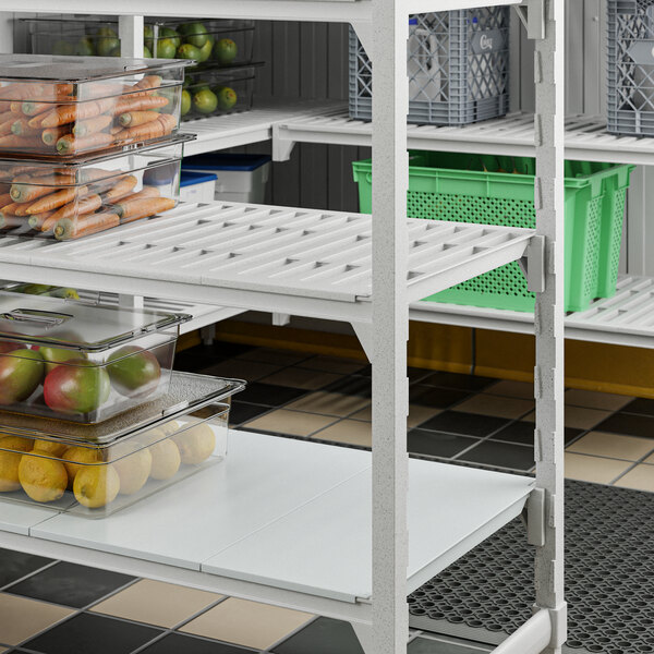 A Cambro Camshelving Premium stationary shelf kit with a mix of vented and solid shelves holding storage bins of fruits and vegetables.