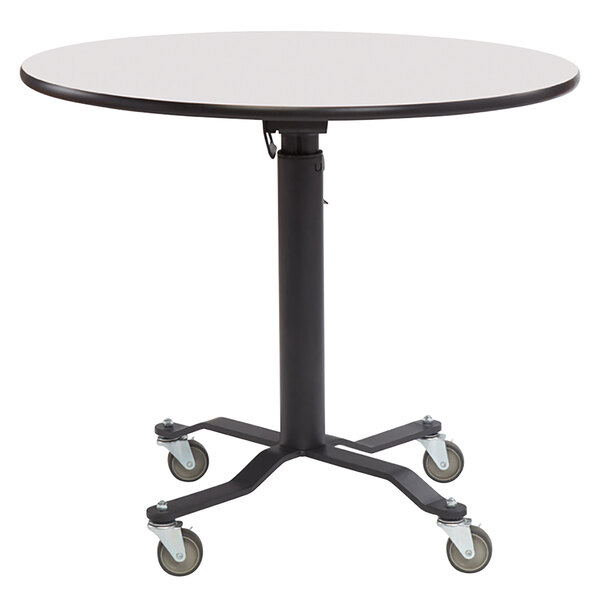 A National Public Seating round cafeteria table with a whiteboard top and black edge and wheels.