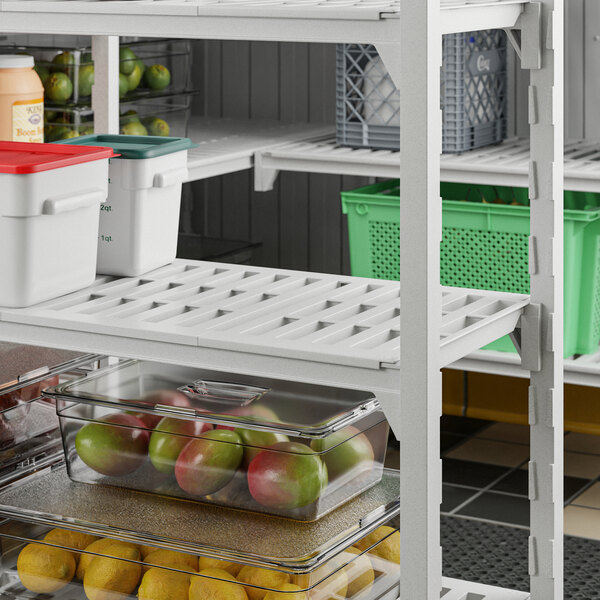 A white Cambro Camshelving storage unit with 4 vented shelves holding fruits and vegetables.