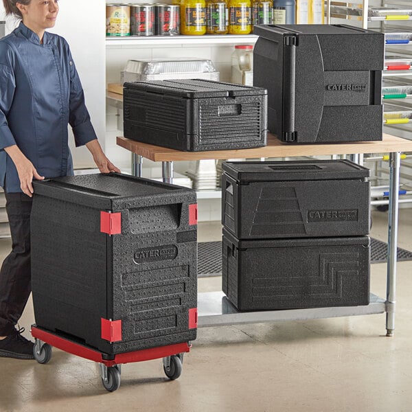 A woman holding a black CaterGator Dash food pan carrier.