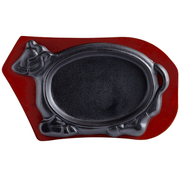 A black oval cast iron skillet with a red turtle head on a wood tray.