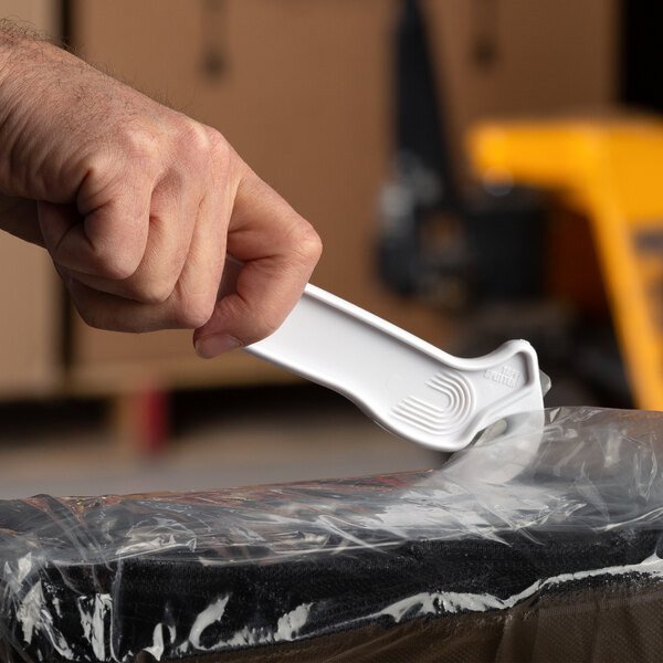 A person using a white Pacific Handy Cutter to cut a plastic bag.