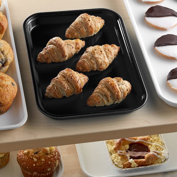 A black Cambro market tray of pastries on a table.