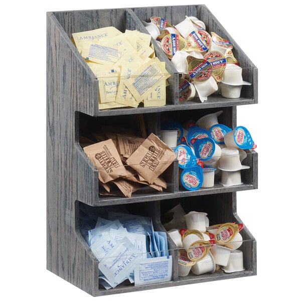 A Cal-Mil double wide wooden condiment display rack with clear bin fronts on a hotel buffet counter filled with condiments.