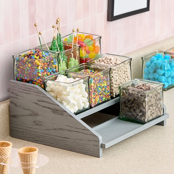 A Cal-Mil Ashwood Gray Oak display with jars filled with candy on a counter.