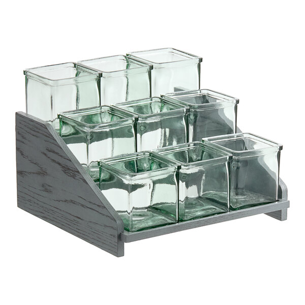 A wooden display stand with glass jars in compartments.
