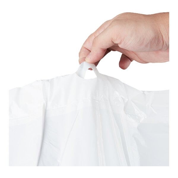 A hand is holding a white plastic bag by its drawstring handle.