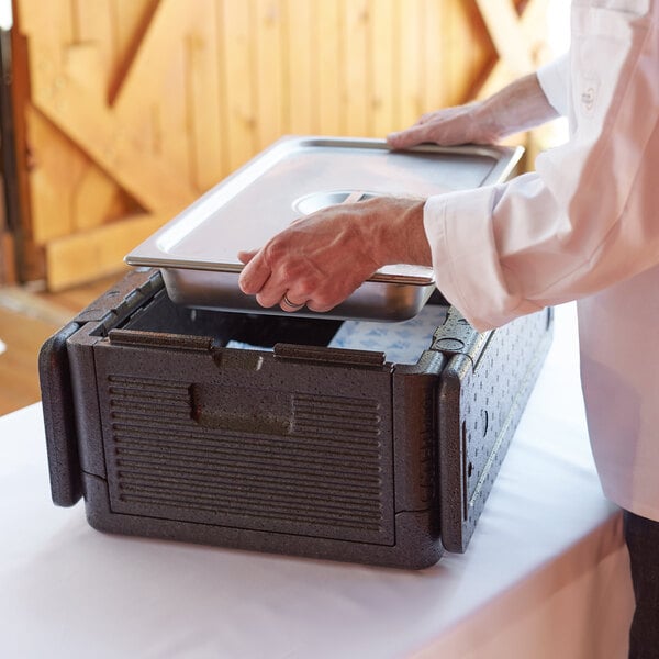 A person using a CaterGator Dash food pan carrier to open a tray of food.