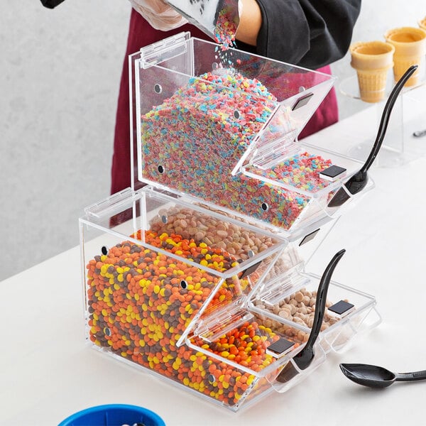 A woman using a Choice candy dispenser to pour candy into a clear container.