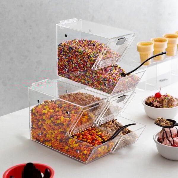 Three clear plastic containers filled with candy and nuts with sprinkles on top.