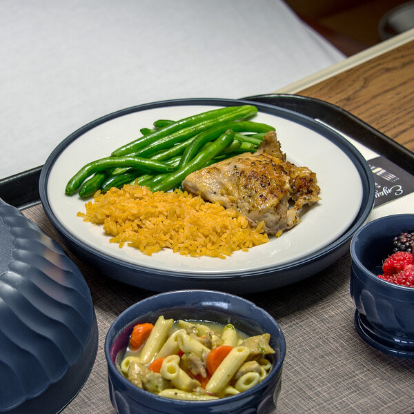 A dark blue Dinex underliner with a plate of food, rice, chicken, green beans, and a bowl of raspberries.