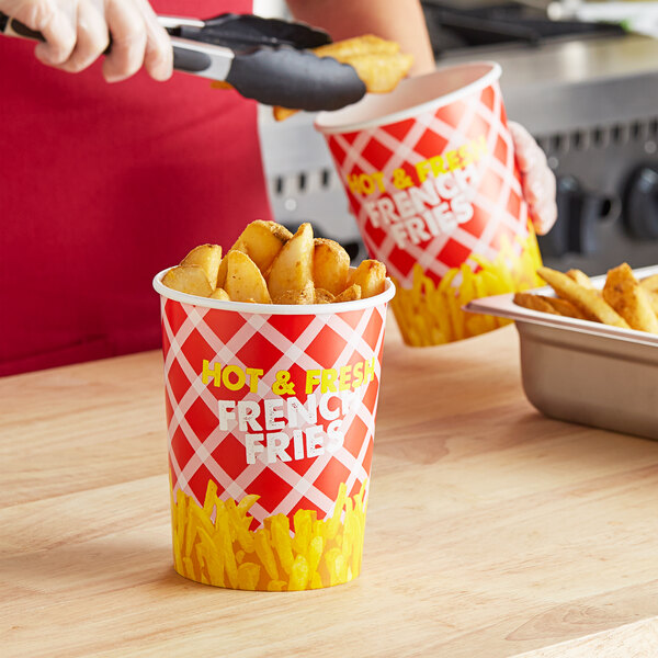 A person holding a Choice red and white cup filled with French fries.