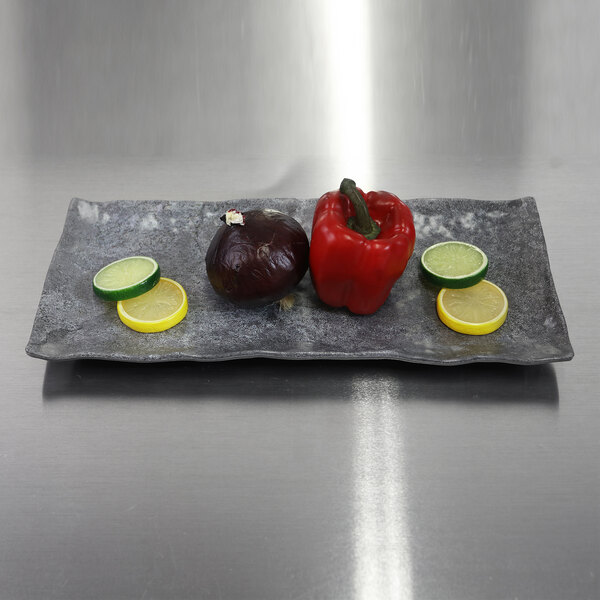 A rectangular Basalt melamine plate with vegetables and a lemon slice on it.