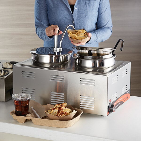 A woman using an Avantco countertop food warmer to serve food.