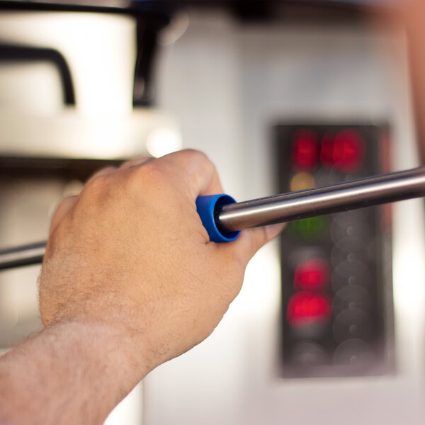 A hand holding a metal pizza peel handle with a blue grip, part of the GI Metal Azzurra Professional 7 Piece Pizza Kit.