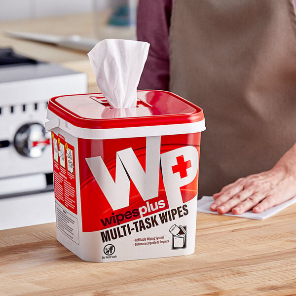 A woman using a WipesPlus multi-task wipe to clean a table.