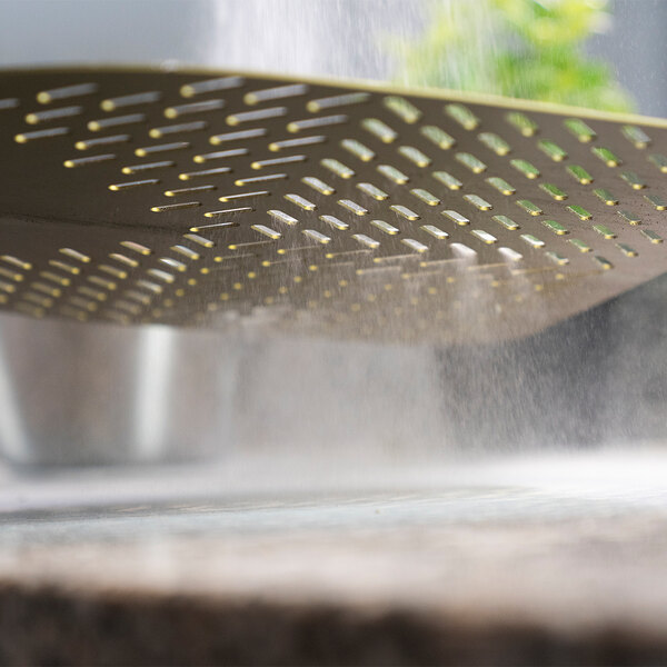 A person using a GI Metal square perforated pizza peel to remove a pizza from an oven.