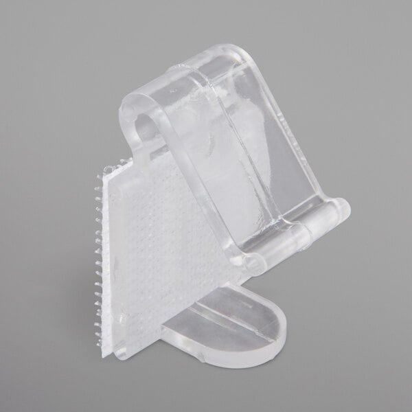 A close up of a Snap Drape clear plastic table skirt clip with hook and loop attachment.
