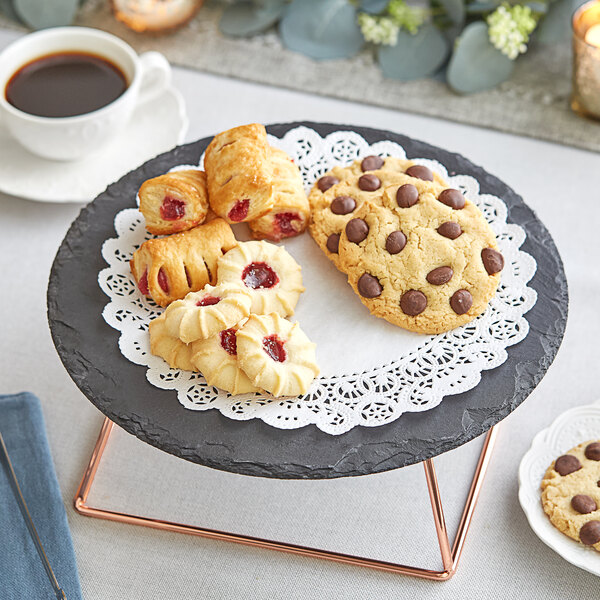 A plate of cookies and Normandy lace doilies on a table with a cup of coffee.