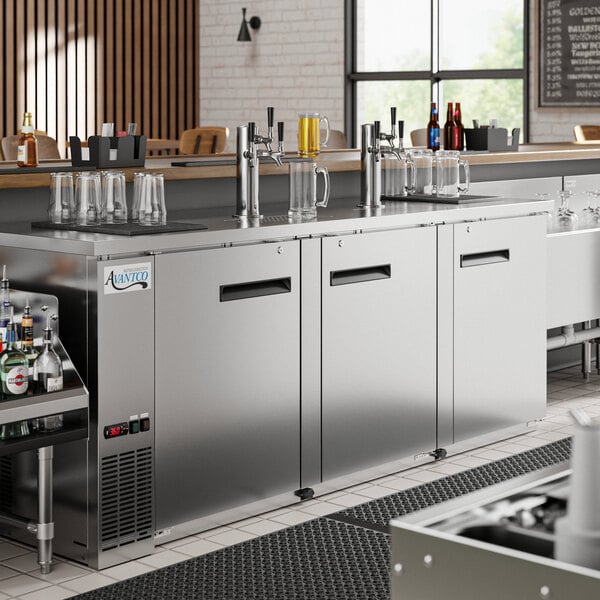 An Avantco stainless steel kegerator with three beer taps on a counter.