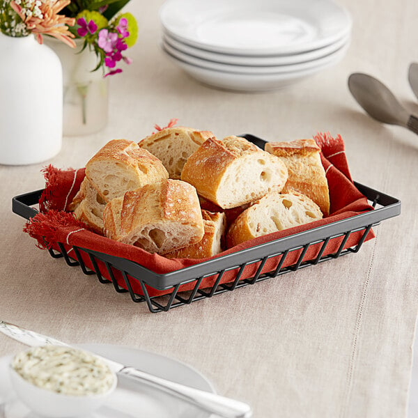 A GET rectangular metal gray wire basket filled with bread on a table.