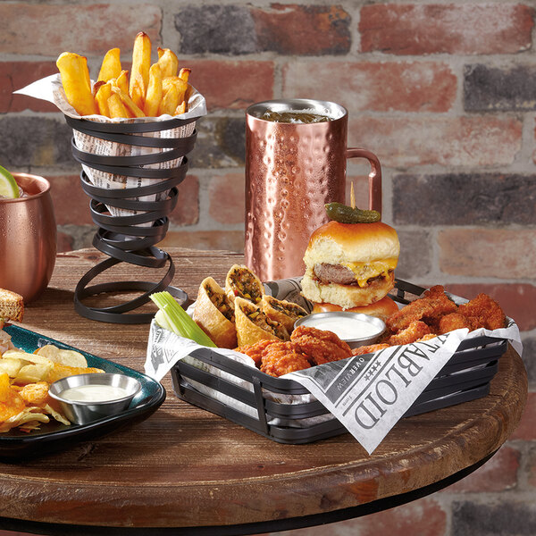 A metal gray wire basket with food on a table.