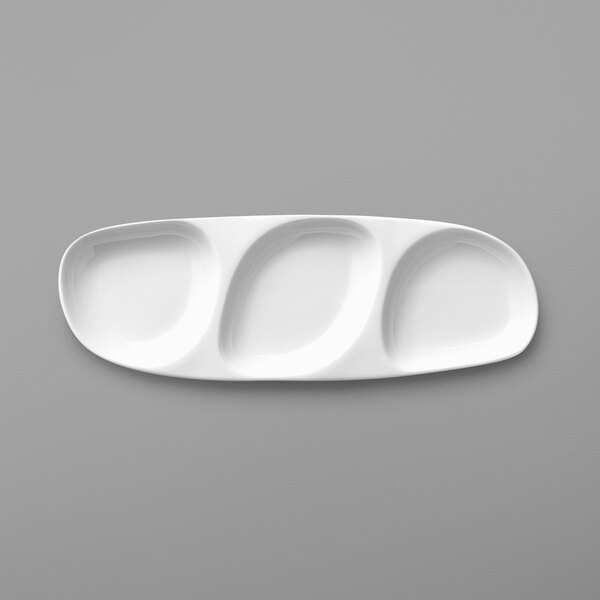 A white oval shaped plate with three small wells on it.