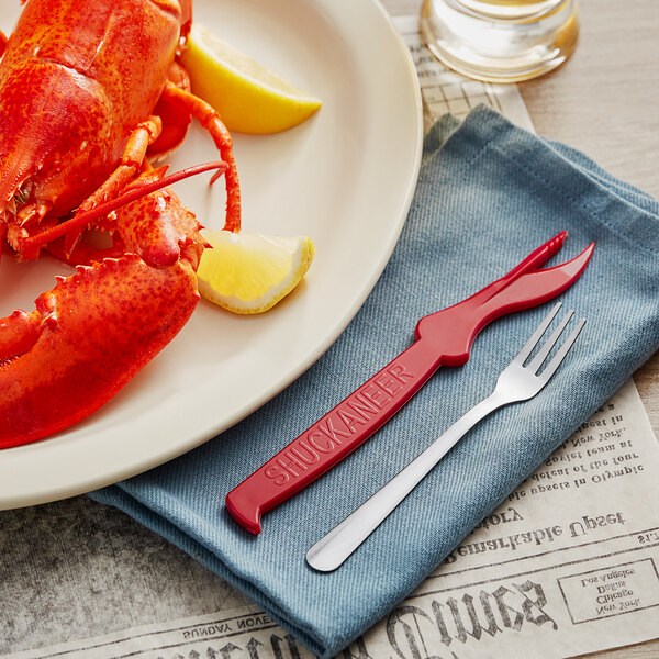 A lemon wedge and shrimp on a plate with a Choice Cocktail Oyster Fork and Seafood Sheller.