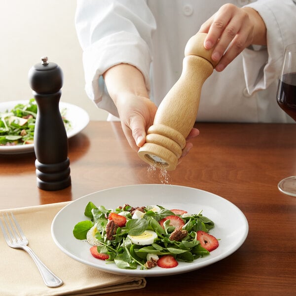 A chef grinds salt onto a salad