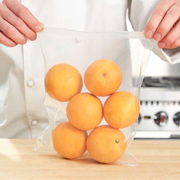 A person holding an LK Packaging plastic bag of oranges.