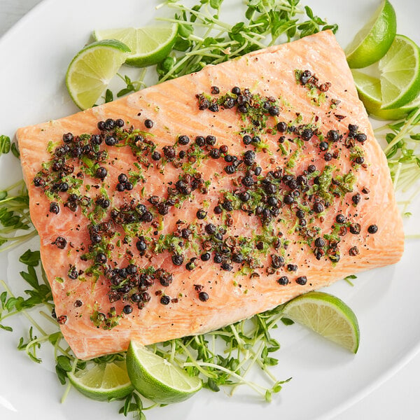 a piece of salmon with limes and greens on a plate