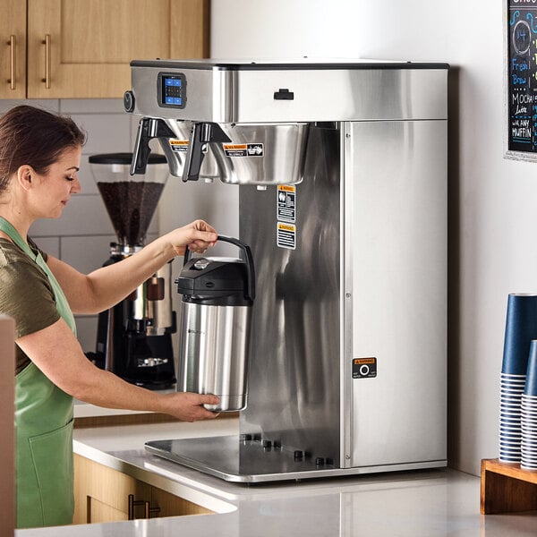 A large commercial twin automatic coffee brewer with a stainless steel finish, designed for brewing coffee into airpots.