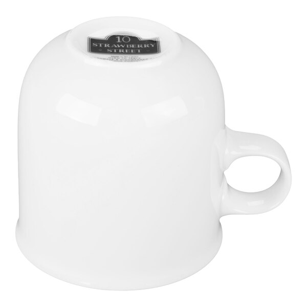 A white porcelain mug turned upside down with a handle visible.