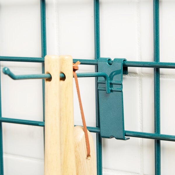 A Metroseal 3 pronged metal hook holding a wooden spoon on a metal grid.