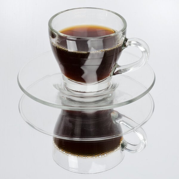 A Libbey glass cappuccino cup filled with coffee on a white saucer.
