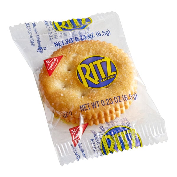 A small, clear plastic package containing two round, golden crackers with a scalloped edge and visible salt on top.