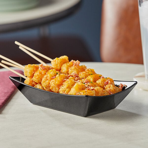 A black Tablecraft serving basket with food on sticks.