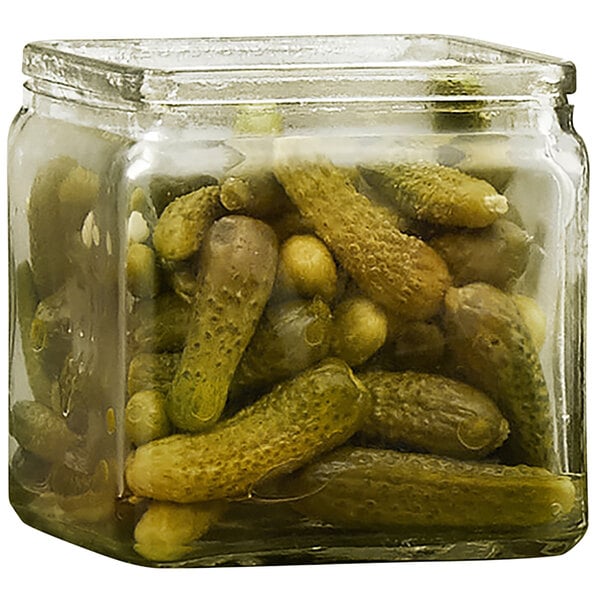 A square glass jar filled with pickles.