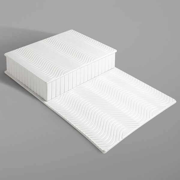 A white rectangular Bon Chef display riser with wavy lines.