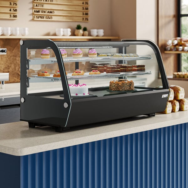An Avantco black refrigerated countertop bakery display case with food on it.