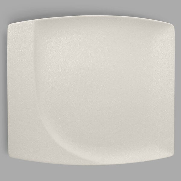 A close-up of a RAK Porcelain sand white square plate with a curved edge.