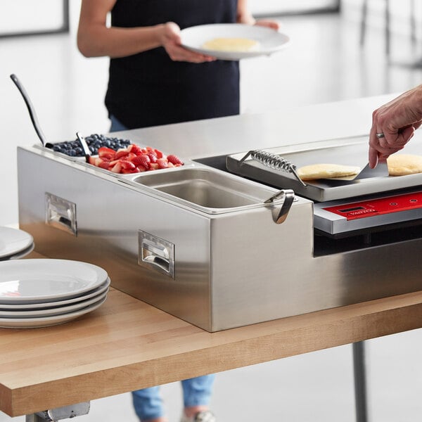 A woman using an Avantco induction pancake station to cook pancakes on a countertop.