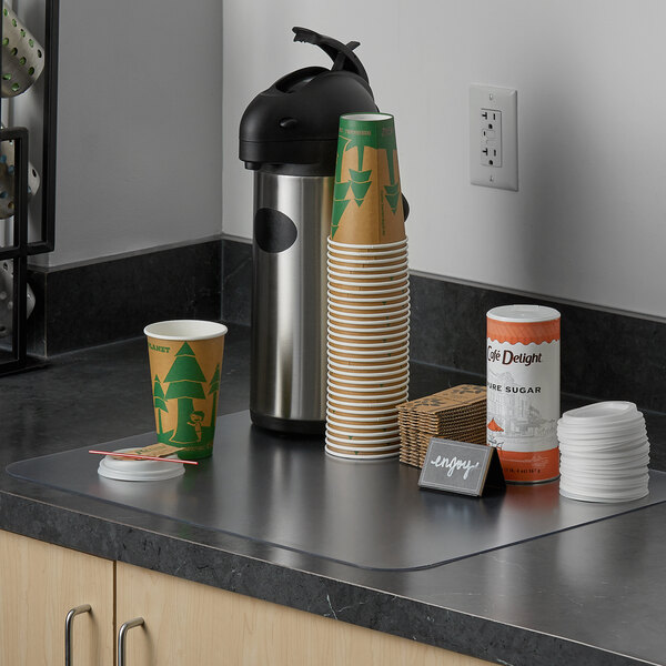 A countertop with a coffee cup and thermos on an ES Robbins countertop mat.