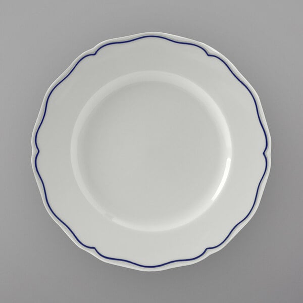 A Tuxton white china plate with scalloped edges and blue trim.