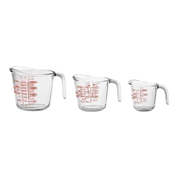A group of three Anchor Hocking clear glass measuring cups with red writing and handles.