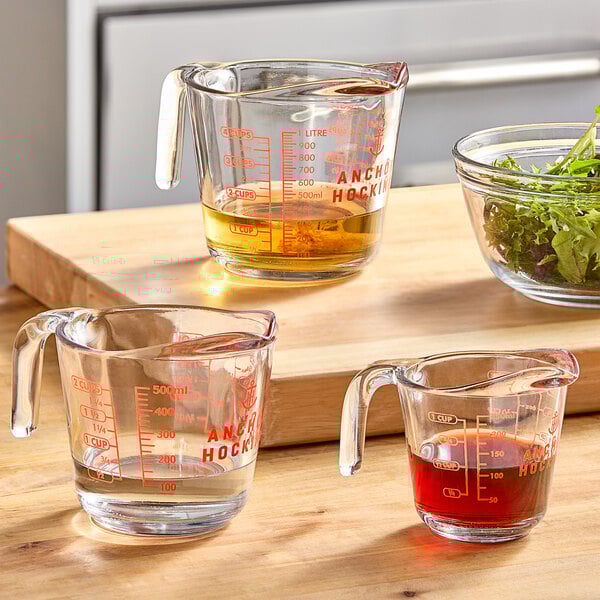 An Anchor Hocking glass measuring cup with yellow liquid inside on a kitchen counter.