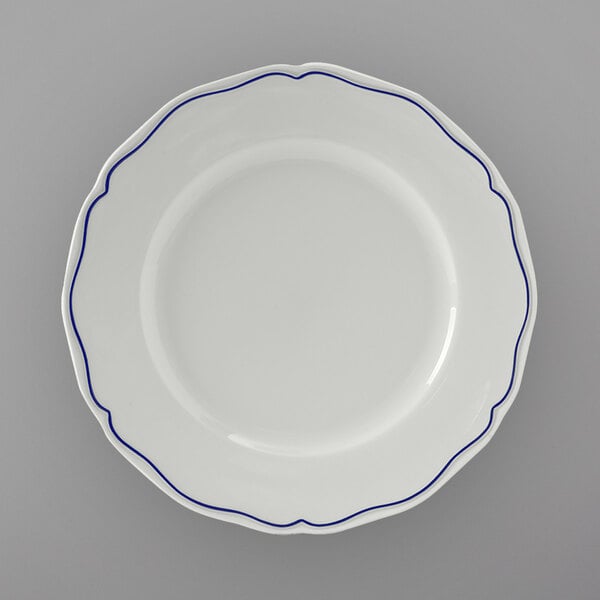 A Tuxton white china plate with scalloped edges and blue trim.