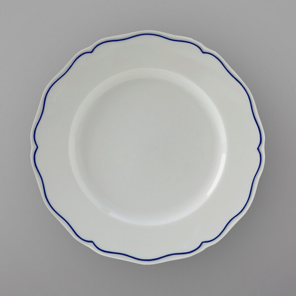 A Tuxton white china plate with scalloped edges and blue trim.