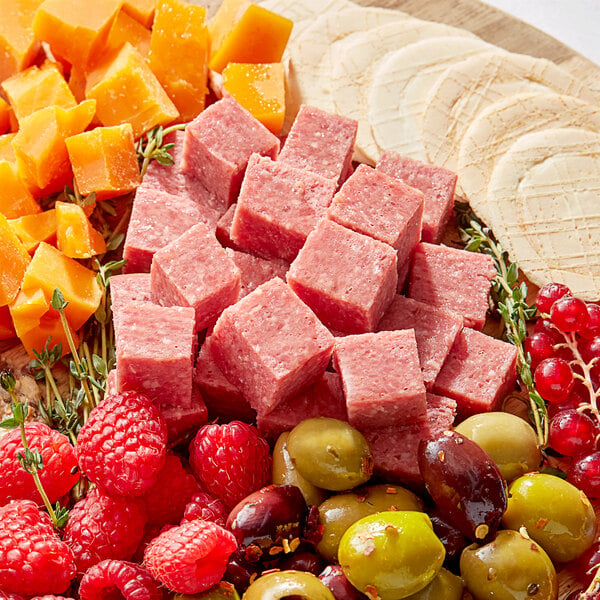 A plate of food with fruit, cheese, and cubes of Kunzler sweet bologna.